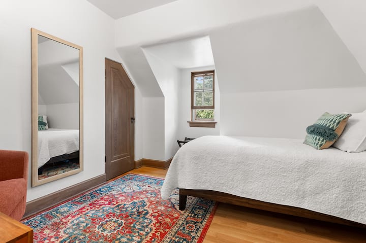 "The Little" offers a Twin Bed with DreamCloud Premier Mattress, closet, luggage rack and comfy barrell chair.