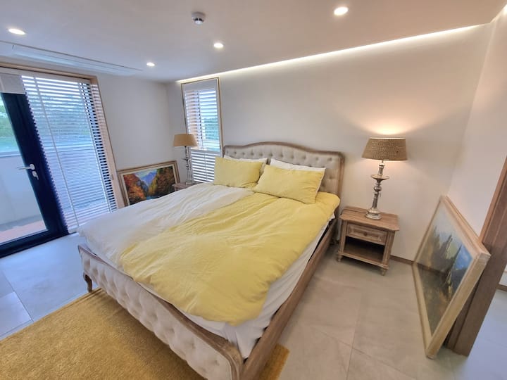 Hii ni mtazamo wa chumba cha 1. Mwanga wa jua unaingia kupitia dirisha na taa ya hila ya kitambaa huongeza mguso.