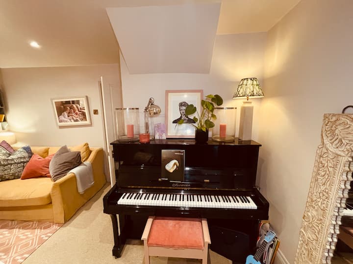 • 	Dhomë ndenjjeje me madhësi mesatare me divan, piano dhe televizor të vendosur në dollap muri, të cilat i përdorim kryesisht për fëmijët që luajnë ose për të parë filma.