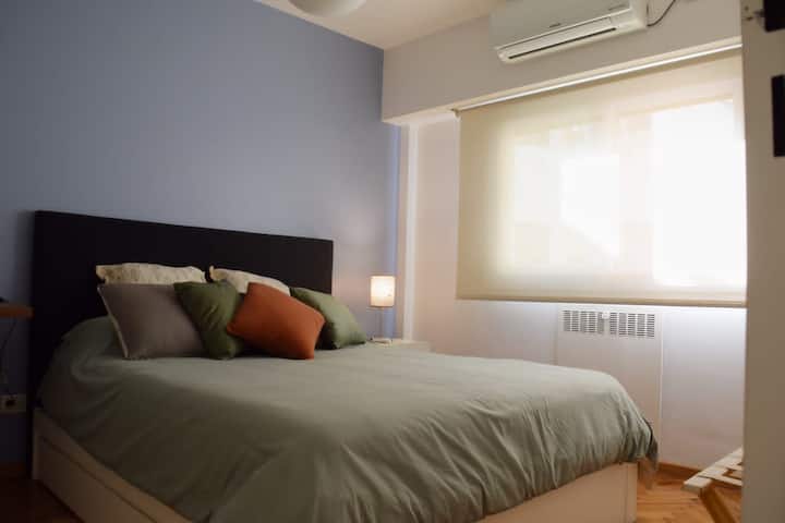 Საძინებელში დგას საწოლი 152 × 203 სმ (1.60 x 1.90), ცივი-ცხელი კონდიციონერი, მსუბუქი მაგიდა და სამუშაო სივრცე.