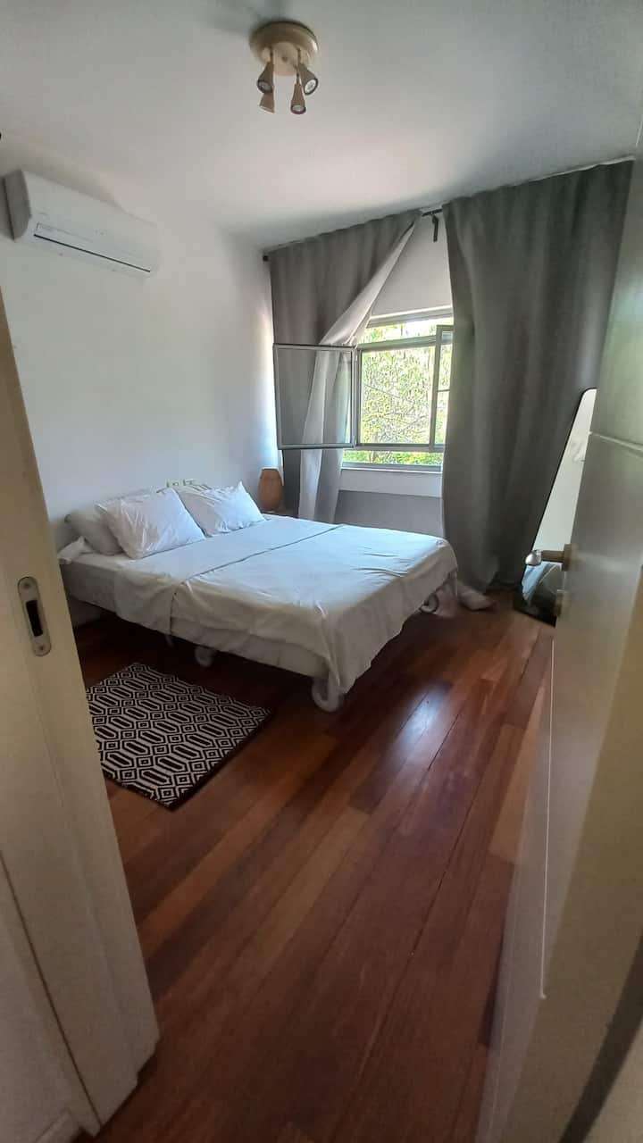 Quarto espaçoso com cama de casal, colchão de espuma de memória, janelas grandes com cortinas de sombra, ar-condicionado e armário.