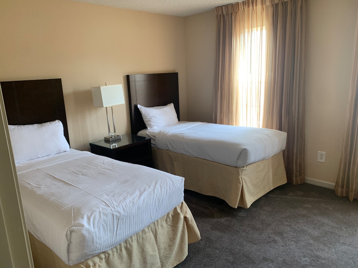 Სასტუმრო საძინებელში დგას ორი კომფორტული საწოლი, რომ დაისვენოთ და დაისვენოთ დასასვენებლად.