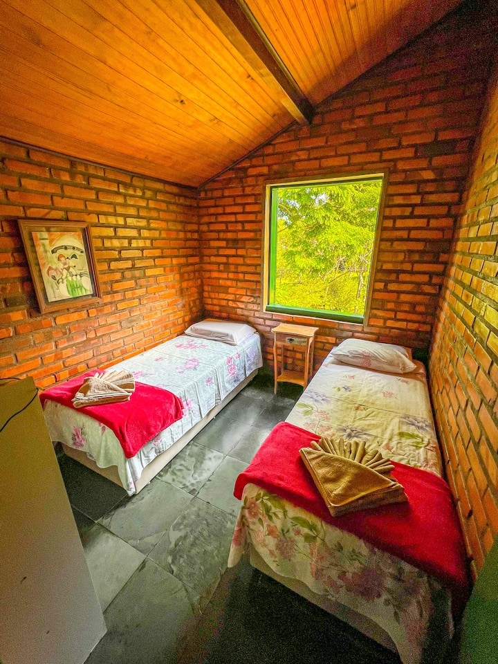 No andar de cima, são dois quartos com camas de solteiro que podem juntar e virar cama de casal! Que tal acordar com essa vista linda para o jardim?