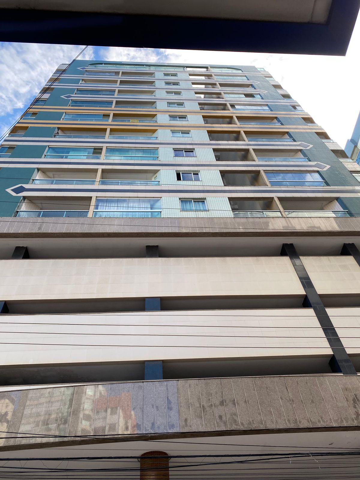 The building features a modern design with multiple floors, showcasing large windows that allow natural light to fill the interior. The exterior presents a blend of light and dark colors, with a structured parking area visible at the base.