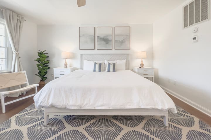 Escape to our serene first-floor bedroom, where calming light blue and white hues create a relaxing oasis complete with a king bed and crisp white linens.