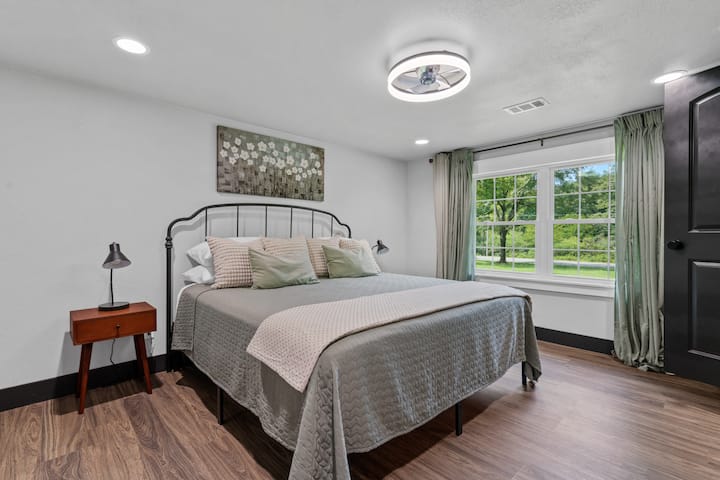 Primary bedroom with king bed, TV, and ceiling fan.  Bedside lamps have USB ports and phone chargers. 