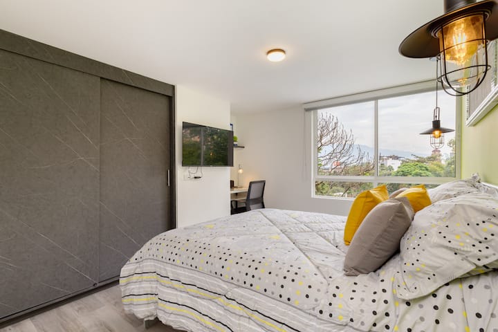 Dormitorio con armario personal, TV y espacio de trabajo.