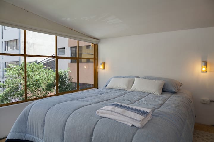 cama de dos plazas y media con vista al jardín del centro cultural