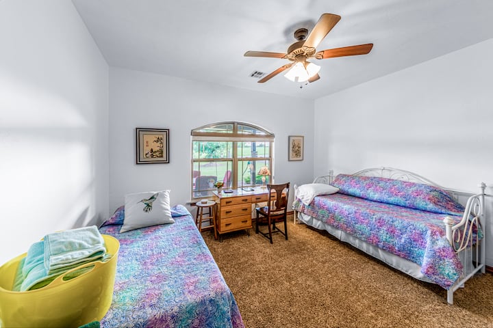 This room features two single beds, each with a brand-new Purple mattress for a restful night's sleep.  The window offers a peaceful view of the covered porch, bringing in natural light and charm.