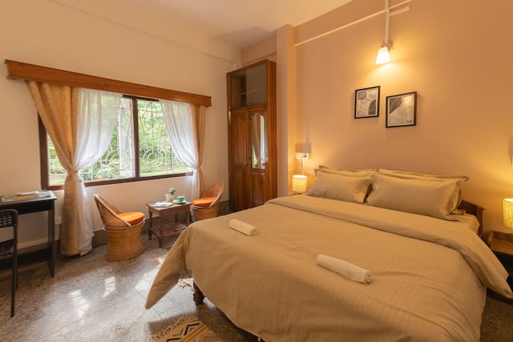 3rd Bedroom with King-sized bed, work space, garden view and shared bathroom. 