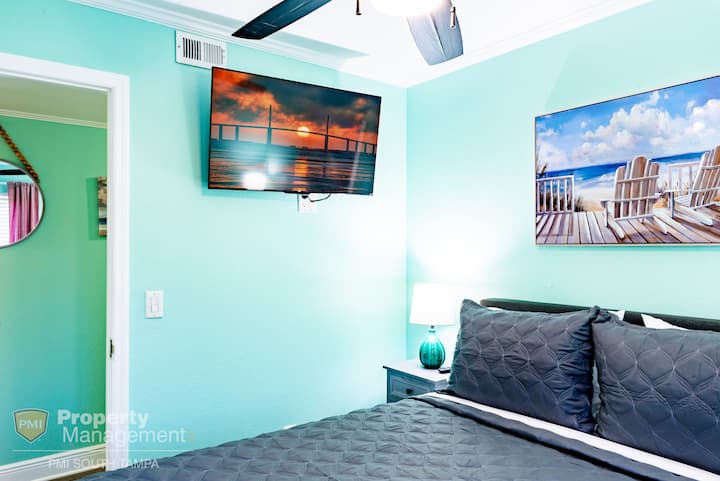 The king-sized bed in the room is complemented by the modern touches, including the wall painting and decorative nightstands.