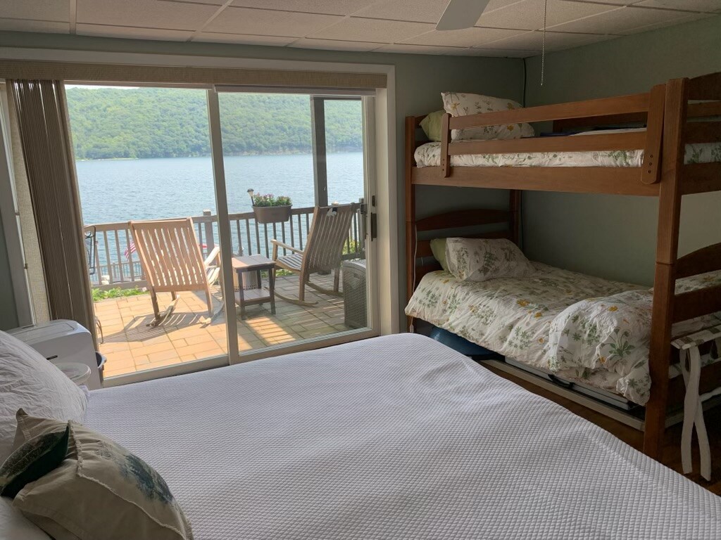 เตียงสองชั้นในห้องพักพร้อมเตียงขนาดคิงไซส์ (หรือเตียงแฝด 2 หลัง) ที่ชั้น 1 พร้อมม่านบังแสงบนประตูบานเลื่อน 
เก้าอี้โยกไม้สักและโต๊ะถังไวน์บนลานด้านนอก 