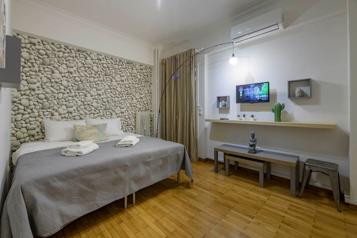 A cosy and stylish bedroom featuring a luxurious king-sized bed, a modern smart TV, and a serene pebble-inspired accent wall. Perfect for relaxation with warm lighting and thoughtful decor creating a tranquil retreat.