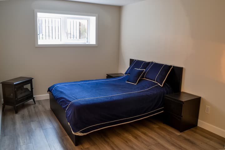 Dormitorio en el sótano con cama tamaño queen y chimenea eléctrica.