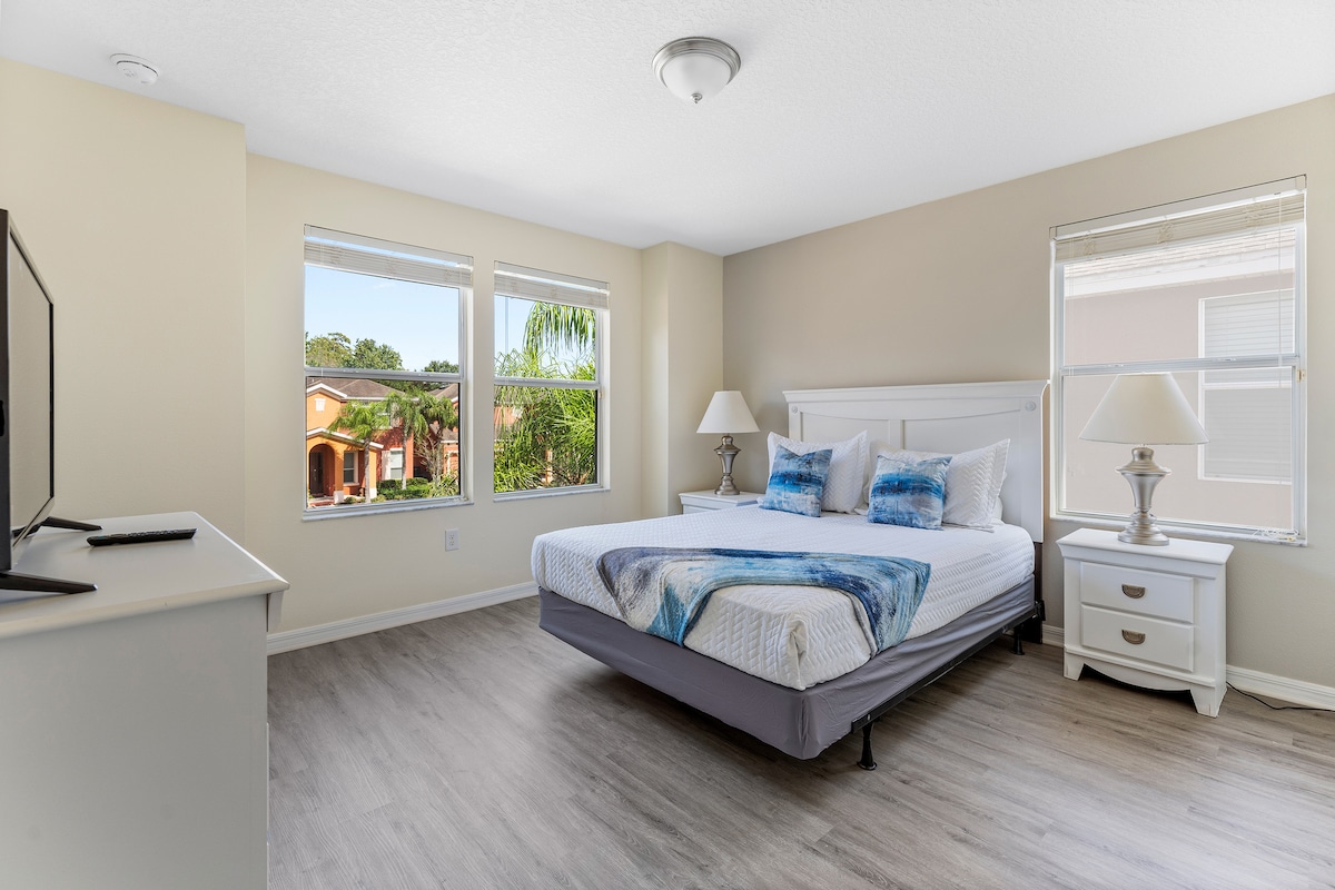 Dormitorio tamaño queen con TV y decoración moderna azul y blanca. 