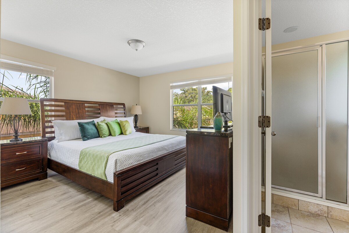 Hermoso dormitorio tamaño king con detalles de ropa de cama verde. 