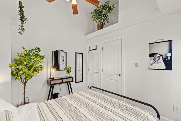 This stunning bedroom has a cozy queen bed, access to the patio, and beautiful greenery all around.
