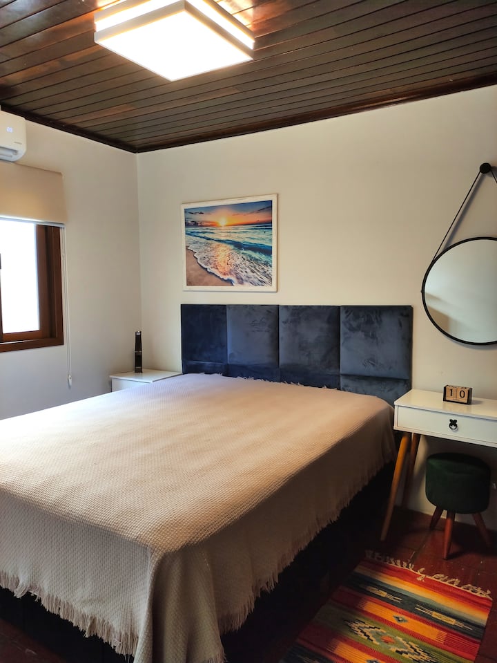 Habitación 02: una cama tamaño queen con caja, TV y aire acondicionado.