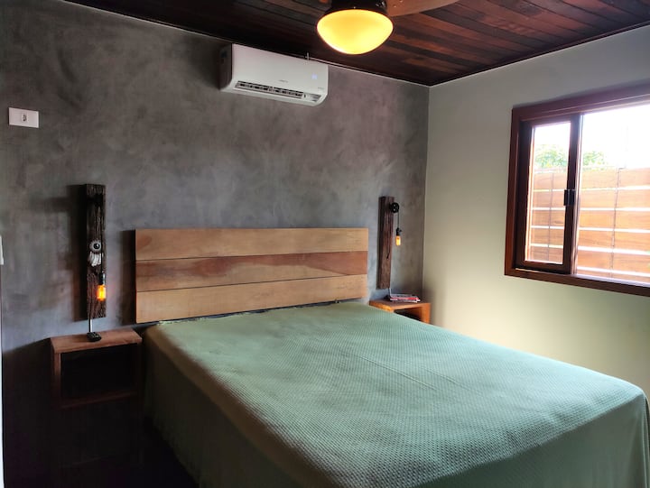 Suite interior (dormitorio 01): cama tamaño queen, TV y aire acondicionado.