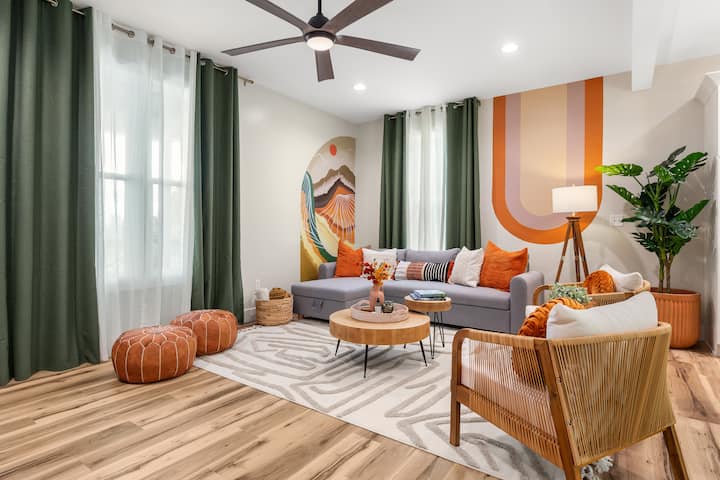 أجواء بوهو في غرفة المعيشة هذه مع جدارياتنا المخصصة (مرسومة يدويًا من قبل فنان محلي!) بألوان ترابية ناعمة، والكثير من الوسائد المريحة ومساحة للتسكع. أريكة للنوم (بحجم الملكة) وستائر تعتيم. 