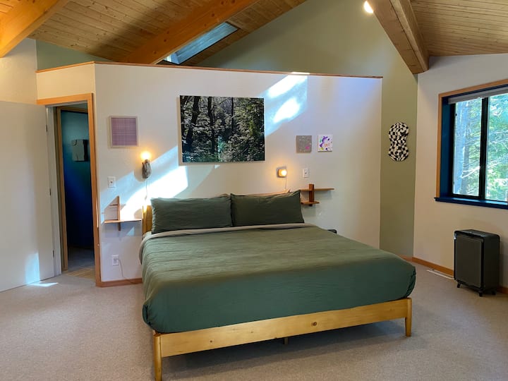 ห้องนอนหลักพร้อมวิวป่าและทางเข้าส่วนตัวไปยังดาดฟ้าและอ่างน้ำร้อน