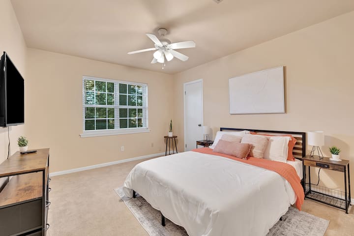 Un dormitorio adornado con una cama tamaño king, un ventilador de techo, un televisor y una ventana, que ofrece un refugio cómodo y bien equipado.
