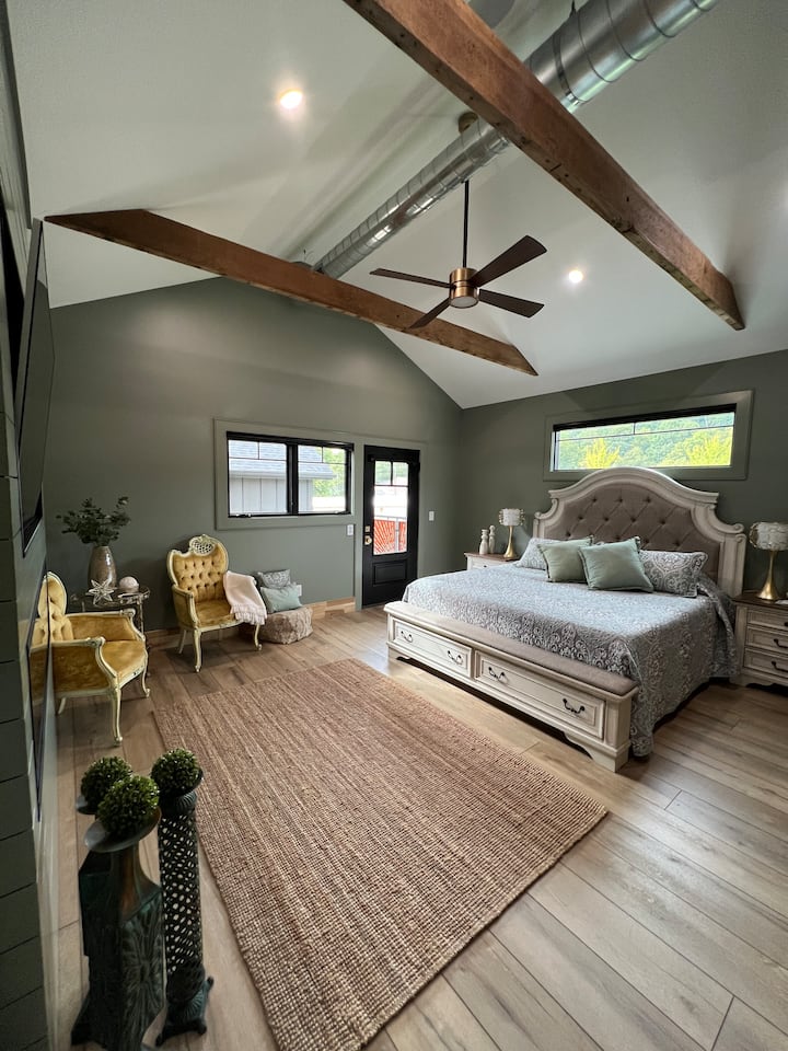 King Master Bedroom with upper deck access, electric fireplace, smart tv, and sitting area. It also has room darkening automated blinds. 