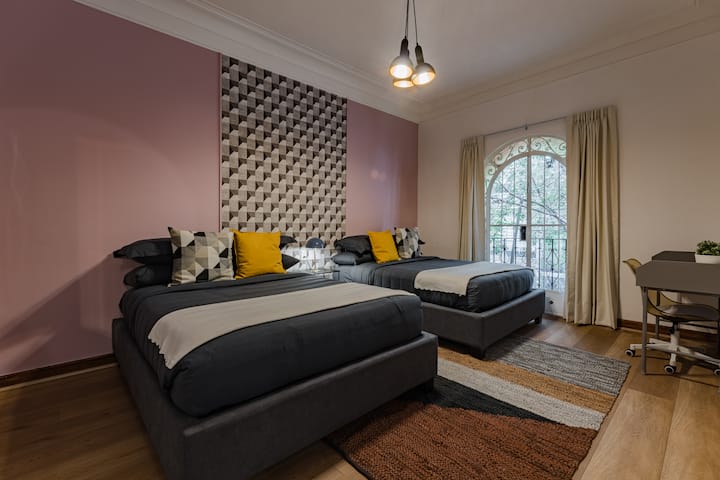 Une chambre à coucher à l'ambiance sombre associe des cadres de lit foncés à un mur d'accent géométrique audacieux.