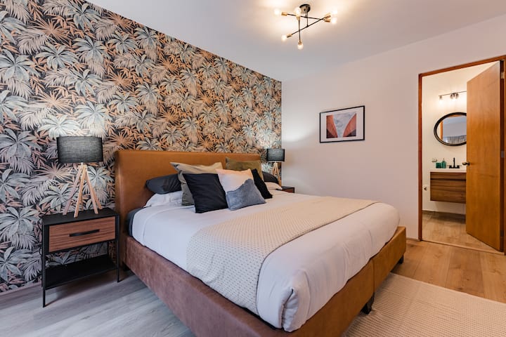 Une chambre avec du papier peint à fleurs et un cadre de lit en bois chaleureux.
