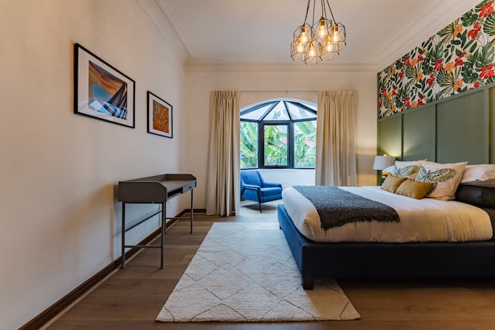 Un papier peint à fleurs et un luminaire suspendu encadrent cette chambre qui donne sur le jardin.