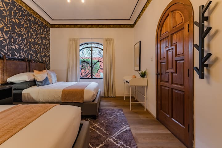 Un coin chambre coloré avec du papier peint à fleurs et une porte en bois rustique à proximité.