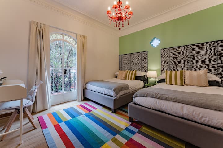 Une chambre joyeuse associe un mur d'accent vert à un tapis à rayures colorées.