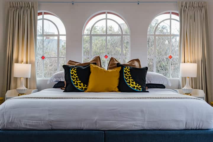 Des coussins aux motifs éclatants illuminent cette chambre sous de grandes fenêtres arquées.