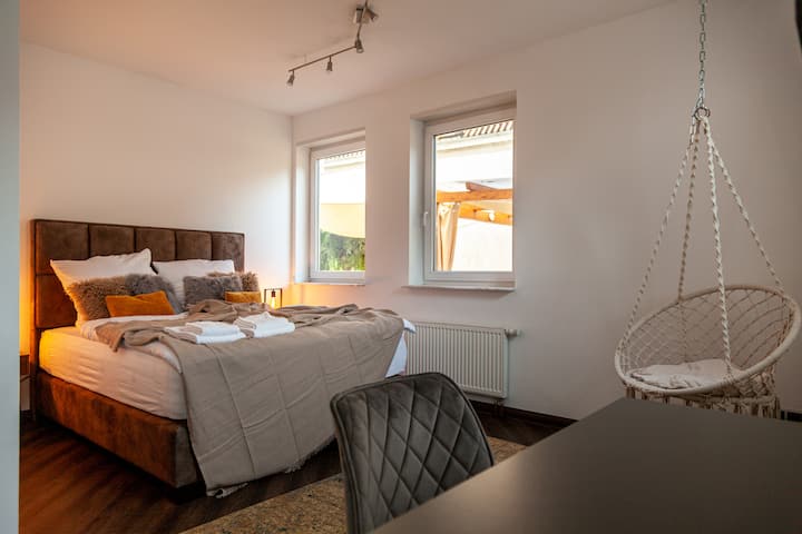 Სიმშვიდის ოაზისი მაღლა: ხედი ჩვენს მეორე საძინებელში მიმზიდველი ყუთის ზამბარიანი საწოლით და მცურავი დასაკიდი სკამით – იდეალური ადგილია კარგი ძილისა და დასვენებისთვის.