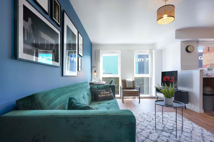 Una sala de estar de planta abierta equipada con un cómodo sofá, sillón y una TV inteligente de 50 pulgadas con suscripción a Netflix incluida