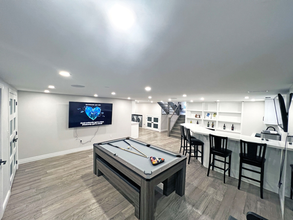This stylish entertainment room is designed for fun and relaxation, featuring a sleek pool table as the centerpiece and a large wall-mounted TV for watching movies or playing games.
