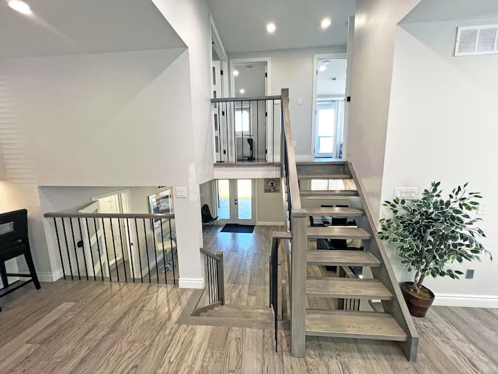 This staircase seamlessly connects the home's different levels, featuring modern metal railings and warm wood steps. The open design enhances the spacious feel, making it both a functional and visually appealing centerpiece of the living space.
