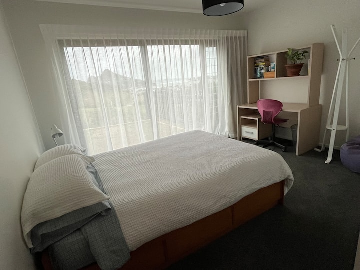 Dormitorio con cama doble, escritorio y silla.  También hermosas vistas hacia el puerto de Tairua para disfrutar desde esta cama.