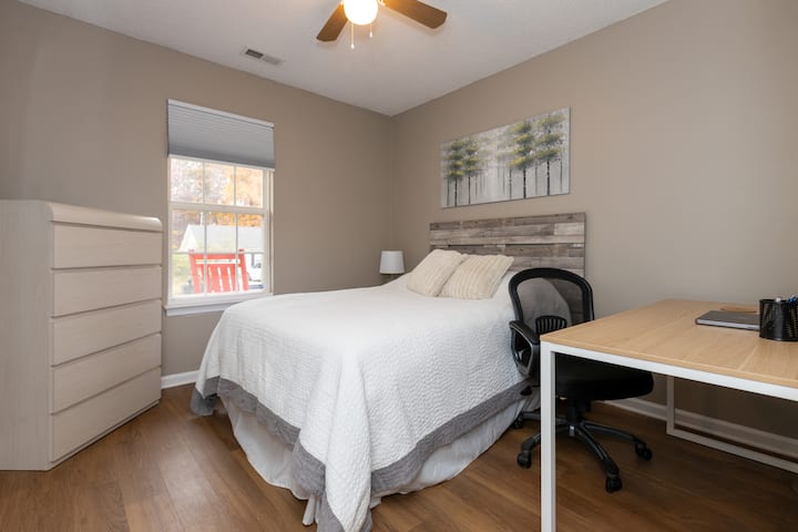 Dyshek i fortë me madhësi të plotë me hapësirë pune, dollap, dollap dhe televizor të madh me ekran të sheshtë.