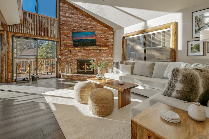 The living room welcomes you with a seamless blend of comfort and style. This expansive, open-concept space features high, vaulted ceilings with exposed wooden beams that add a touch of rustic charm, perfectly balanced by sleek, contemporary finishes