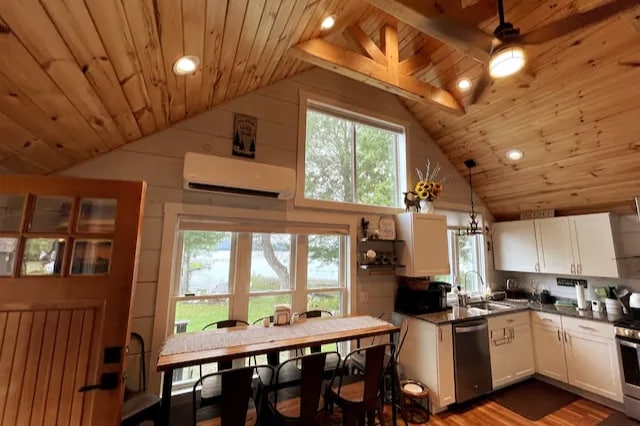 A bright kitchen area features high wooden ceilings with exposed beams. Large windows overlook the lake, allowing natural light to fill the space. A wooden dining table with black chairs sits adjacent to modern white cabinetry and stainless-steel appliances, creating a functional and inviting atmosphere.