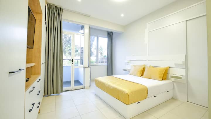 Chambre principale climatisée avec beaucoup de rangement et balcon privé ainsi que des rideaux de jour et de nuit