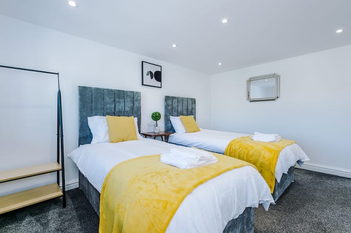 Dormitorio doble luminoso con camas cómodas y detalles en amarillo fresco.