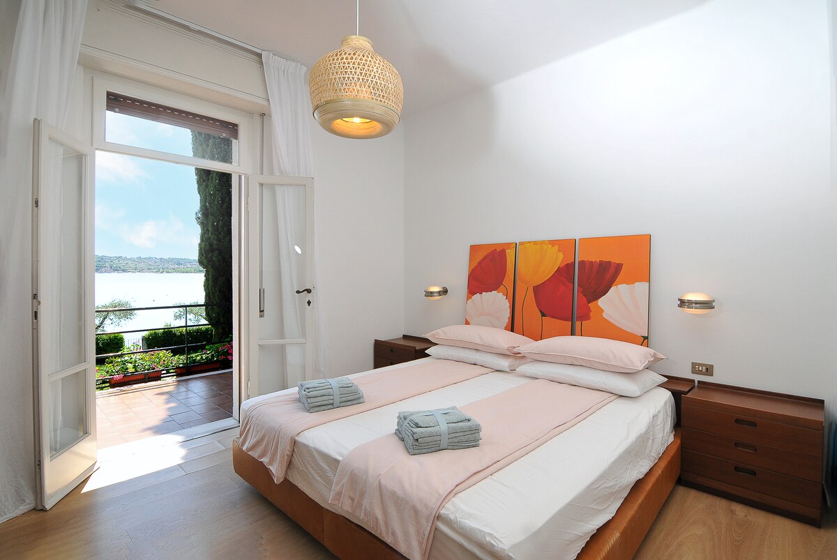 Tercer dormitorio con vistas al lago y a la terraza, cama matrimonial, dos mesitas de noche, vestidor y armario.