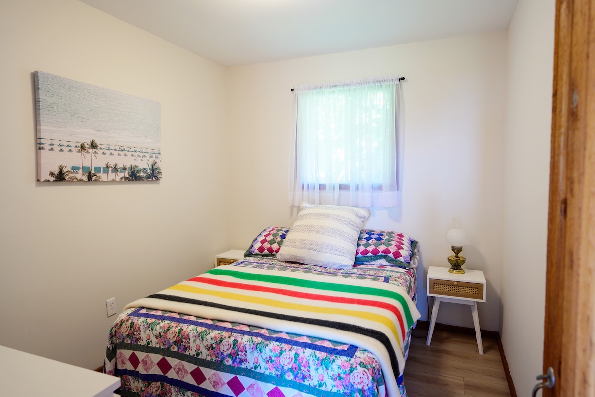 Pokojný spánok s oceánskym vzduchom a útulnou posteľnou bielizňou. Táto spálňa má pohodlnú posteľ s farebnou patchworkovou prikrývkou a ikonickou dekou Hudson's Bay. Nájdete tu aj komodu, zrkadlo a kôš na bielizeň pre väčšie pohodlie. 