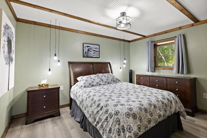 Main floor queen bedroom with electric color-changing fireplace, comfortable layout, and direct access to laundry area.