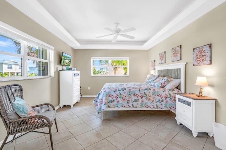 Une chambre adaptée à une reine et un point de vue sur les palmiers qui se balancent et le canal.
Commode, tables de nuit, chaise, télévision et ventilateur de plafond dans chaque chambre.
