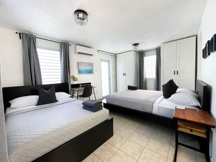 Geräumiges Hauptschlafzimmer mit zwei weichen Betten, perfekt für Gruppen, Geschwister oder Reisende, die sowohl Komfort als auch persönlichen Raum schätzen. Die im weit entfernten Foto gezeigte Tür führt zur Terrasse. 