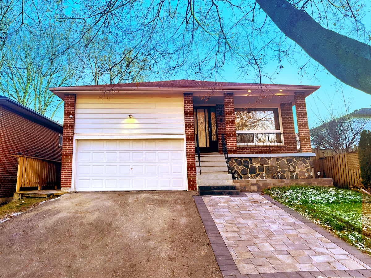 The exterior of the house showcases a modern brick facade with a stone-accented entryway. A spacious driveway leads to a two-car garage, while a paved walkway guides guests towards the front entrance. Surrounding greenery adds to the inviting atmosphere.