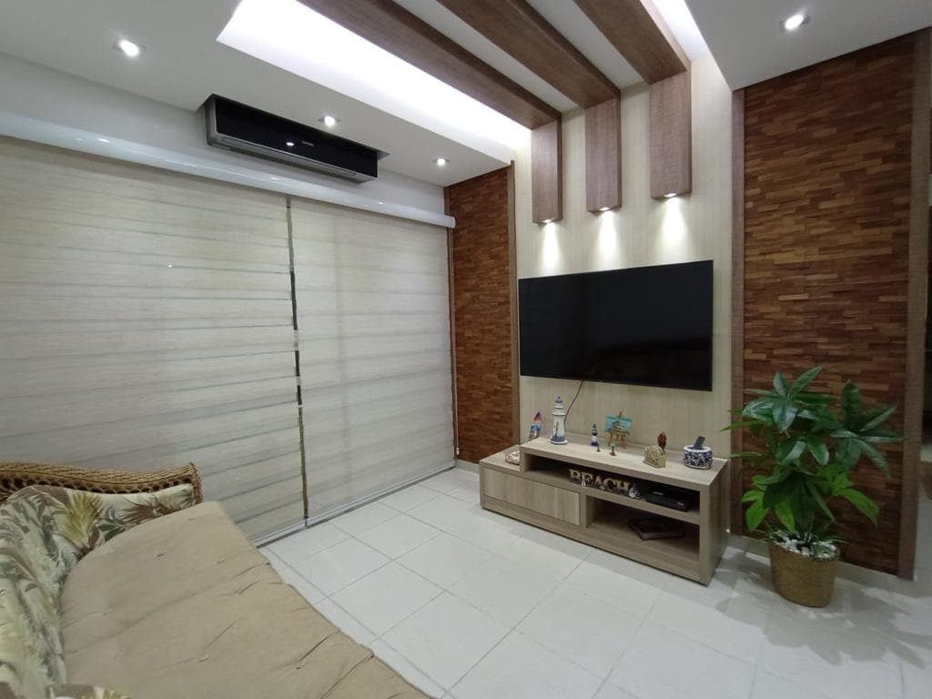 غرفة تلفزيون مع تلفزيون ورف وأريكة وتكييف هواء 